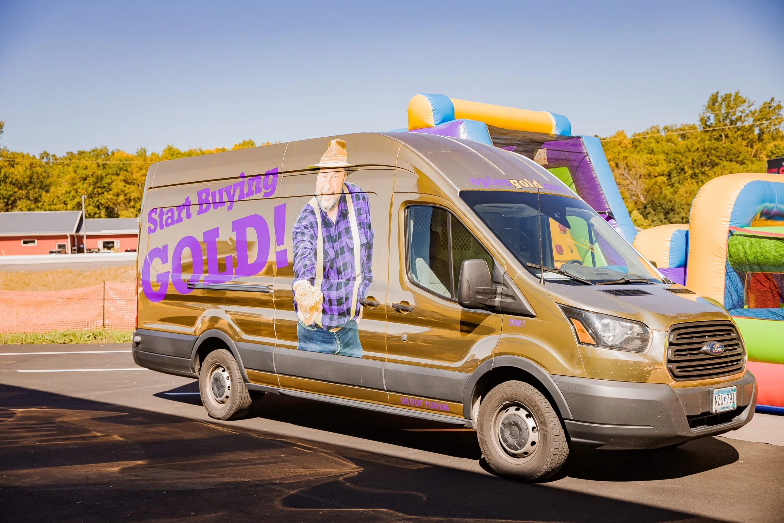 Five men wearing purple shirts stand in front of a gold van displaying the message "Start Buying Gold!